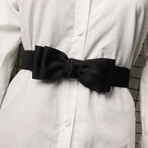 Close-up of black elastic waist belt with double bow decoration on white shirt