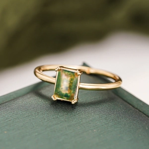 Macro shot of gold ring with rectangular green moss agate in classic prong setting