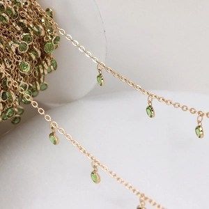 Macro shot of gold plated DIY jewelry chain with translucent green round pendant dangles