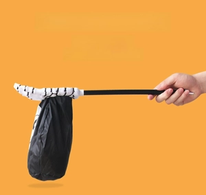 Detail of Halloween candy bag with skeleton hand handle held against orange background