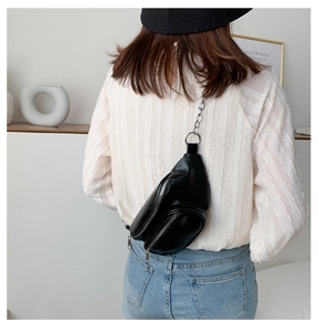 Back view of model wearing a black leather belt bag with silver chain and zipper detail