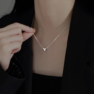 Detail of S925 sterling silver heart pendant necklace on model with polished mirror finish