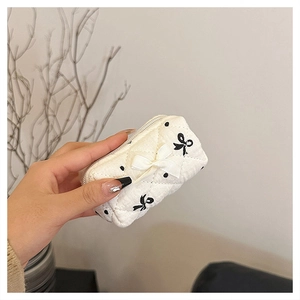 Mini quilted cotton cosmetic bag with black polka dots and a white ribbon bow detail