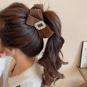 Detailed back view of a brown fabric bow hair clip with sparkling rhinestones decoration