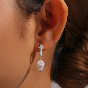 Detail of s925 silver star pearl earrings featuring a white baroque pearl drop on model