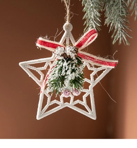 Close-up of white star ornament with red bow, pine cones, and faux snow details