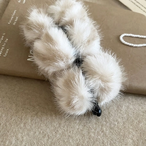 Vue détaillée de la pince à cheveux en peluche beige sur fond de papier kraft