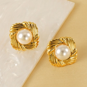 Detailed close-up of vintage baroque 18K gold pearl stud earrings on gold silk fabric