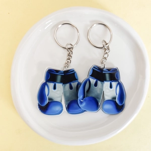 Top view of two blue boxing glove keychains on a white ceramic plate background