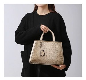 Dettaglio della borsa beige in pelle goffrata coccodrillo con cornice in metallo e charm