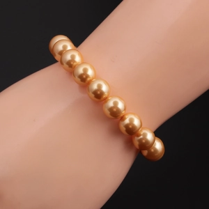 Detail of 10mm champagne gold shell pearl bracelet on a display model with black background