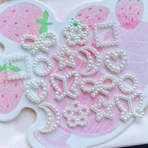 Detailed view of white pearlescent DIY craft charms in assorted geometric shapes