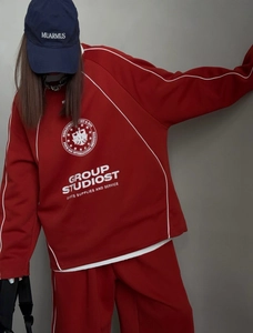 Close-up of dark red tracksuit with contrast white trim and logo on the sweatshirt