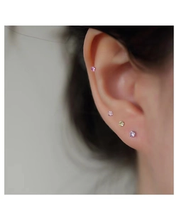 Detail of four colorful S999 silver mini round cubic zirconia stud earrings on ear