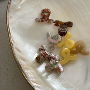Set of 9 colorful acetate mini hair claws in a decorative shell dish for girls
