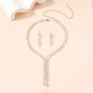 Macro shot of gold bridal jewelry set with rectangular cubic zirconia tassel necklace and earrings