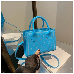 Détail du sac à main matelassé bleu brillant avec clous cœur dorés et cuir verni élégant