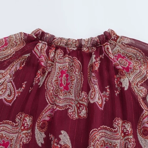 Détail d'une robe bordeaux à imprimé paisley avec fils dorés et encolure à volants