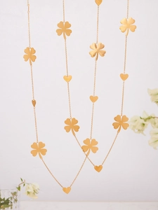 Detail of layered gold necklace featuring lucky four-leaf clover and heart-shaped charms