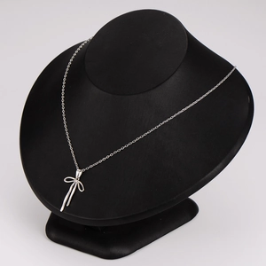 Elegant silver bow pendant necklace displayed on a black bust mannequin stand
