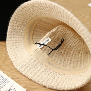 Detail of beige knit bucket hat interior with adjustable drawstring and sweatband