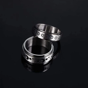 Detail view of silver spinner rings with sun, moon, and floral cutout patterns on black background