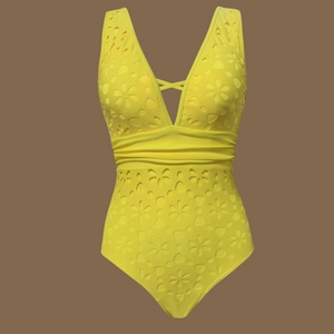 Detail of laser-cut floral pattern and deep V-neckline on yellow one-piece swimwear