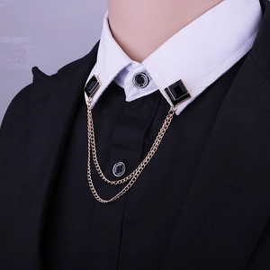 Close-up of golden geometric collar chain with black square gems on suit and shirt