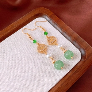 Detailed shot of vintage gold flower earrings with pearls and green beads on a tray