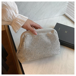 Detailed macro shot of a white rhinestone shell clutch bag held in a hand