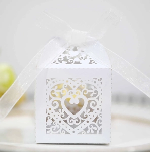 Macro shot of white laser-cut hollow heart candy box with an elegant organza ribbon bow