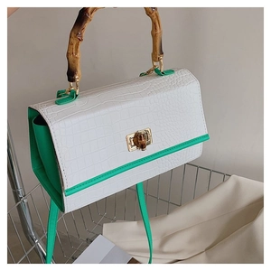 Detail of crocodile pattern handbag with bamboo handle and turn-lock closure