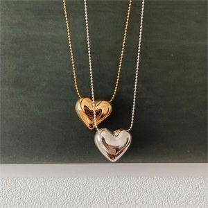 Close-up of gold and silver heart pendants on beaded chains with polished metal texture