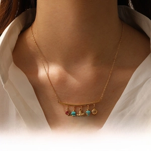 Detail view of a gold-plated layered necklace with starfish, shell and blue stone charms
