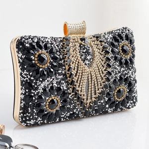 Detail of evening clutch featuring black gemstones and golden rhinestone wing buckle
