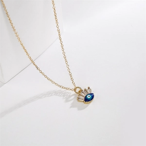 Macro detail of gold-plated evil eye pendant with crown design and zircon inlays