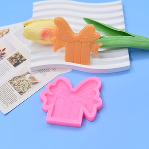 Detailed view of pink bow gift box silicone mold with orange finished fondant cake piece