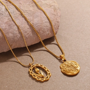 Minimalist gold daisy and tulip pendant necklaces on natural stone background