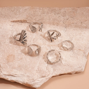 Detailed view of a 6-piece silver seashell and starfish adjustable ring set on stone