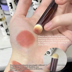 Macro shot of round silicone lip brush blending red lipstick for a matte finish