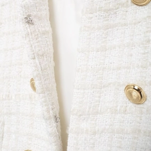 Elegant white tweed vest with golden double-breasted buttons and textured fabric weave