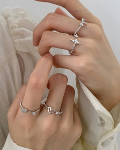 Detail of silver rings featuring heart, bow, and star charms with micro-inlaid diamonds