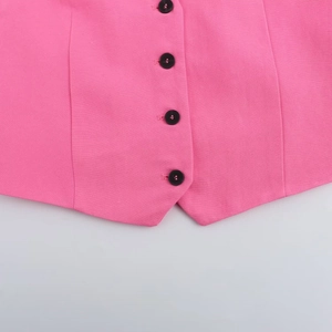 Détail de l'ourlet du gilet rose avec tissu texturé et quatre boutons noirs verticaux