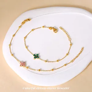 Titanium steel clover bracelets with green and pink zircons on stone display