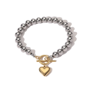 Silberne Perlenarmband mit goldener Herzanhänger und T-Verschluss auf weißem Hintergrund
