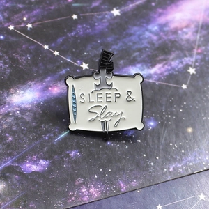 Enamel brooch with sword and pillow design featuring SLEEP & Slay on starry card