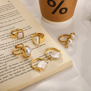 Detailed set of five vintage baroque pearl rings in gold finish on a rustic book