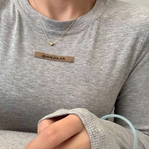 Gray long-sleeve t-shirt with ribbed texture and branded leather patch on the chest
