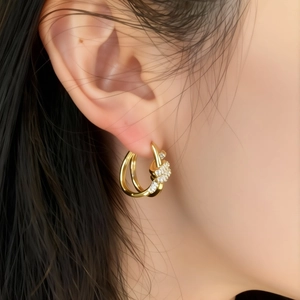 Gold plated knot hoop earrings with sparkling cubic zirconia on a female model