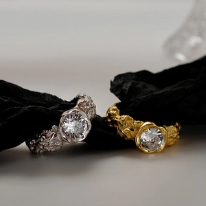 Detail of silver and gold irregular textured rings with sparkling center gemstone